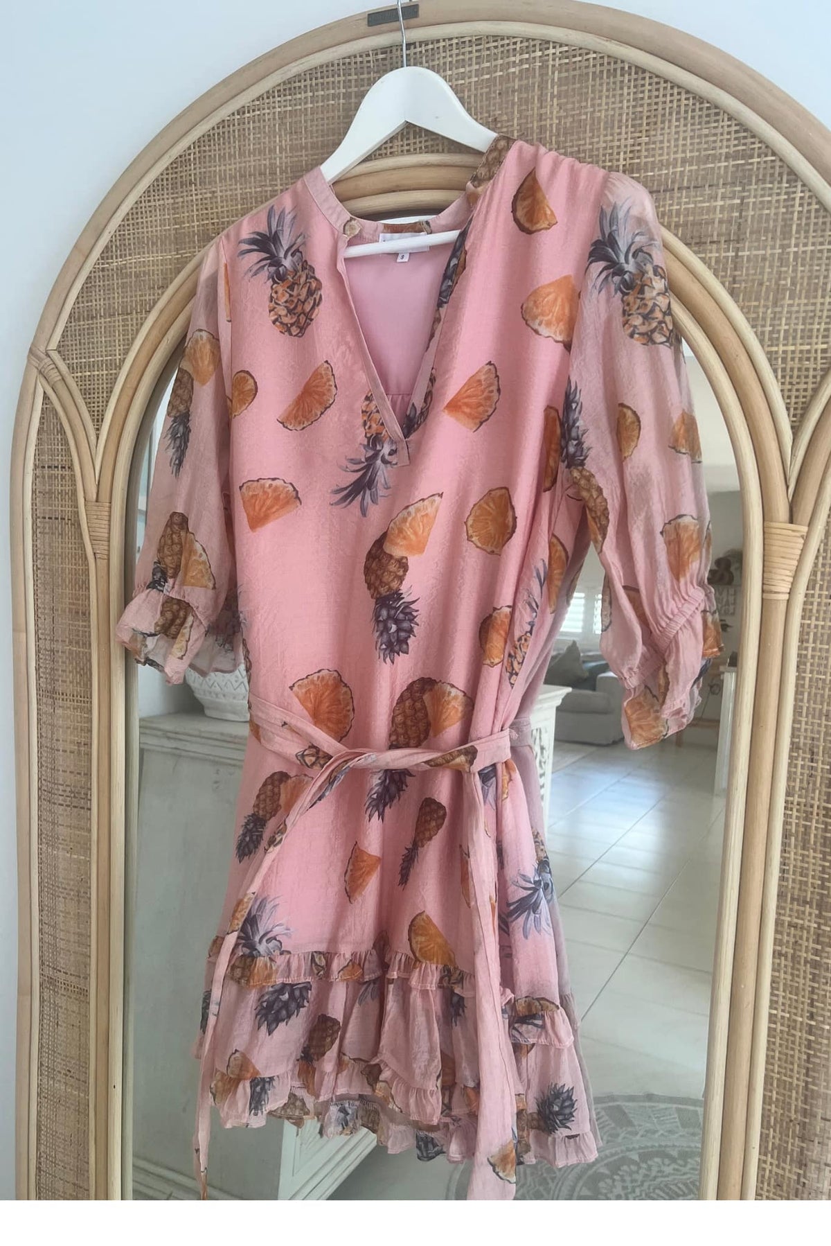 Pink dress with pineapple pattern hanging on a mirror